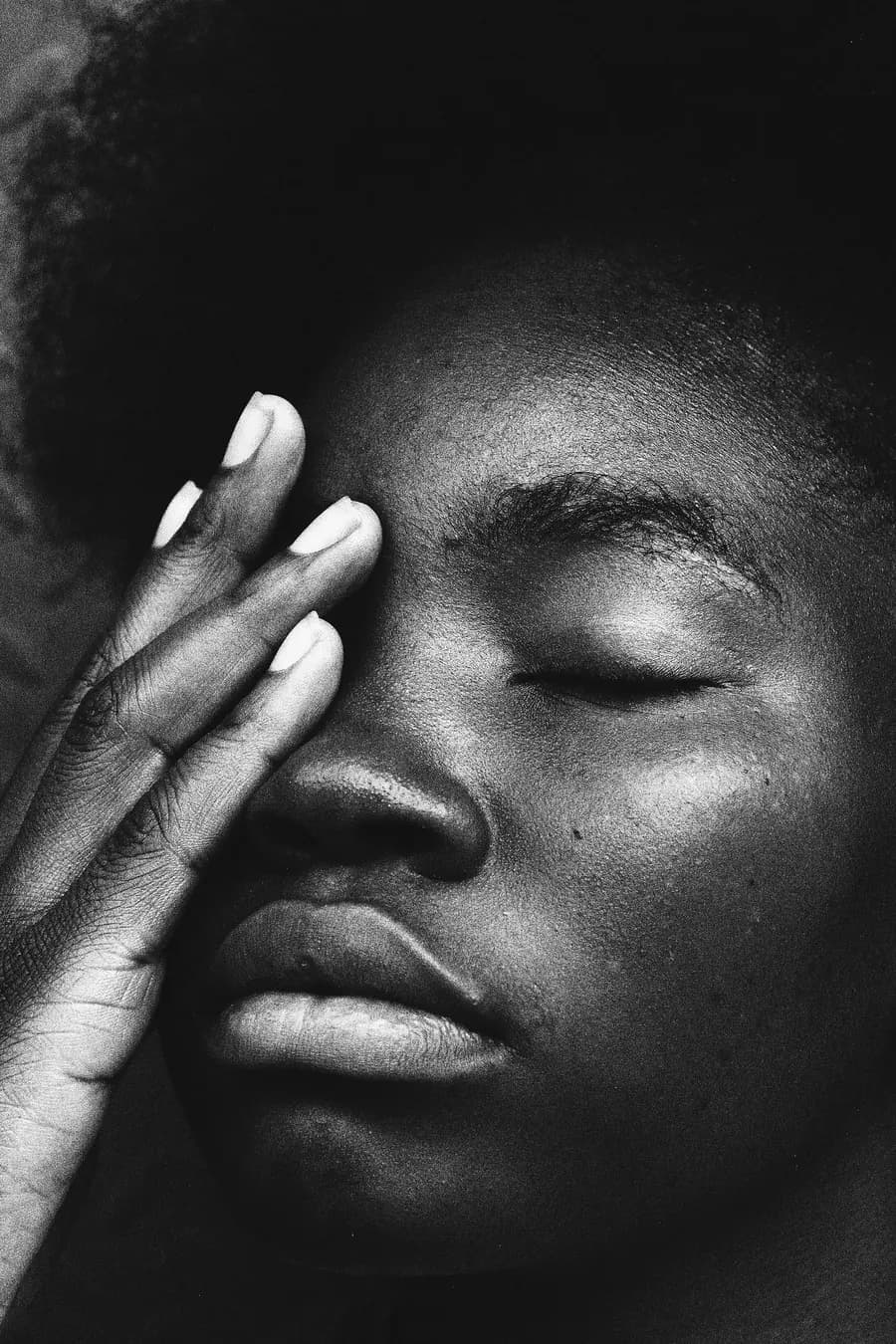Close-up of a woman resting her face in her hand, eyes closed
